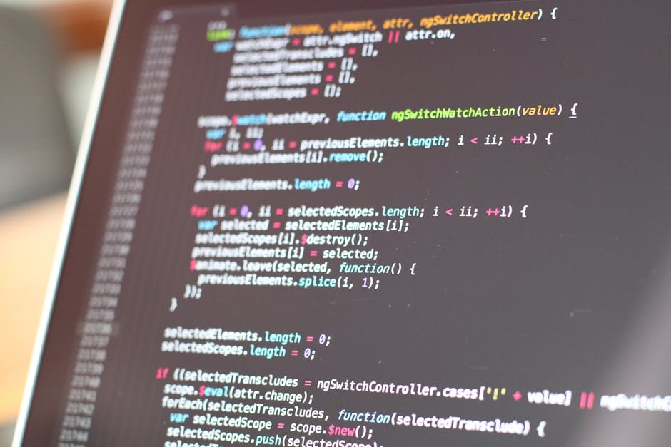 A computer screen displaying a close-up view of a code editor with lines of HTML or CSS code written in multicolored text, primarily red, green, blue, and purple, set against a dark background. The co
